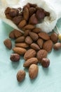 Almonds pour from sackcloth on turquoise wooden background