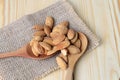 Almonds pour from wood spoon on wooden background