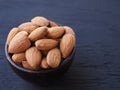 Almonds seeds in wooden bowl on black background. Royalty Free Stock Photo