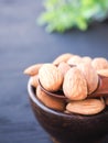 Almonds seeds in wooden bowl on black background.