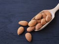 Almonds seeds in wooden scoop on black wooden background. Royalty Free Stock Photo