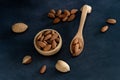 Almonds in a wooden bowl and on a wooden spoon on a black wooden table Royalty Free Stock Photo