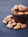 Almonds in wooden spoon on top a bowl over black wooden background. Royalty Free Stock Photo