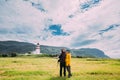 Alnesgard, Godoya, Norway. Man And Woman Young Adult Caucasian Tourists Travelers Couple Posing Against Old Alnes Lighthouse In