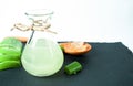 aloe vera gel in glass bottle with sliced aloe vera next to it on black stone background Royalty Free Stock Photo