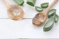 Aloe vera gel in a wooden spoon placed on a white wooden