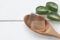 Aloe vera gel in a wooden spoon placed on a white wooden
