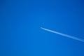 alone airplane flying in clear blue sky with white condensation trails Royalty Free Stock Photo