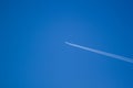 alone airplane flying in clear blue sky with white condensation trails Royalty Free Stock Photo