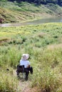 Alone Asian Thai Woman relaxing and sitting on camping chair in the grass field near Stream in tropical forest of Thailand.