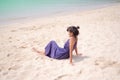 Alone asian woman sitting on sand beach at coast with blue sea.