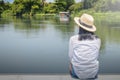 Alone Asian woman wear weave hat and white shirt with sitting on wooden terrace. Royalty Free Stock Photo