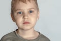 Alone beautiful little boy with big blue sad eyes looking right to the camera. Royalty Free Stock Photo