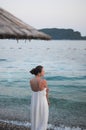 Alone beautiful young woman in a white dress is standing near the sea Royalty Free Stock Photo