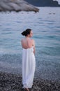 Alone beautiful young woman in a white dress is standing near the sea Royalty Free Stock Photo