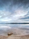 Alone big stone in water close to the beach. Stormy sky above Royalty Free Stock Photo