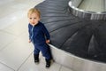 Alone cute caucasian blond toddler boy standing near empty airport arrival terminal luggage conveyor belt. Lost found child.