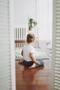 Alone cute toddler girl sitting on floor in the empty room