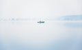 Alone fisherman on the boat in a thick fog on the lake on an autumn morning Royalty Free Stock Photo