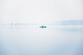 Alone fisherman on the boat in a thick fog on the lake on an autumn morning Royalty Free Stock Photo