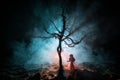 Alone girl in the dead forest at misty night. Silhouette of girl standing between trees under moonlight. Horror Halloween concept Royalty Free Stock Photo