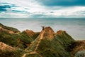 Alone hiker with backpack standing on top of mountain. Strong tourist on the peak of high rocks. Winner with hands up