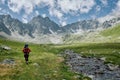 Alone hiker man with backpack is walking by the river among mountains. Extreme tourist in wild nature. Domestic travel Royalty Free Stock Photo