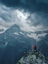 Alone hiker man in red jacket against the gloomy mountain top landscape with thunder cloudy sky Royalty Free Stock Photo