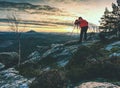 Alone hiker photographer in warm red jacket stand on peak