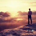 Alone hiker in white shirt and red cap stand on peak of rock in rock empires park and watch over misty and foggy valley to Sun. Th Royalty Free Stock Photo