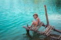 Alone little girl sitting on pier on beautiful blue lake. clean blue water. Wild nature and beautiful place for alone Royalty Free Stock Photo