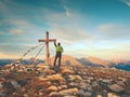 Alone man climber near the summit cross on peak, Dolomite Alps, Austria. Sunny windy evening.