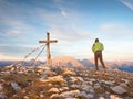 Alone man climber near the summit cross on peak, Dolomite Alps, Austria. Sunny windy evening.