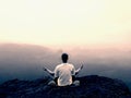 Alone man is doing Yoga pose on the rocks peak within misty morning Royalty Free Stock Photo