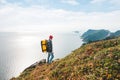 Alone man expeditor wearing professional backpack standing on the edge cliff mountain above sea and looking on epic high landscape Royalty Free Stock Photo