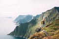 Alone man expeditor wearing professional backpack standing on the edge cliff mountain above sea and looking on epic high landscape Royalty Free Stock Photo