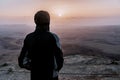 Alone man in israel negev desert admires the view of sunrise. Young male person stands on the edge of the cliff