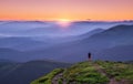 Alone man on the mountain peak looking on mountain valley in fog