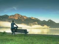 Alone man sits on bench beside an azure mountain lake. Man relax Royalty Free Stock Photo