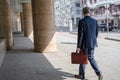 Alone middle-aged gray-haired businessman in a blue suit with briefcase walks on the city street. Royalty Free Stock Photo