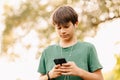 Alone serious teen boy with earphones is looking at his phone while browsing. Royalty Free Stock Photo