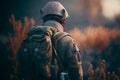 Alone soldier, standing with a backpack, against the backdrop of a autumn landscape