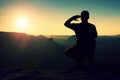 Alone sportsman in black. Tall hiker in squatting position enjoy view at sunset on mountain peak Royalty Free Stock Photo