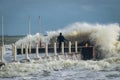 Alone surfer in wetsuits with surfboard on a city pier amid powerful waves in Australia. Concept: confrontation between the Royalty Free Stock Photo