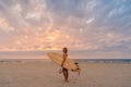 Alone surfer woman on beach with warm sunset tones. Attractive surfgirl with surfboard