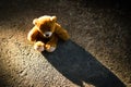 Alone teddy bear sitting on cement floor dark shadow. melancholy regret disappointed cry lonely sad symbols. abandoned child or