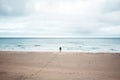 Alone tourist with backpack walks along a deserted beach to the ocean Royalty Free Stock Photo