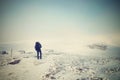 Alone tourist with big backpack and snowshoes walking on snowy path to fog. National park Alps park in Italy. Fogy winter weather.