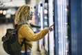 Alone traveler caucasian beautiful woman at the airport or. station choosing and buying food from automatic machine - concept of