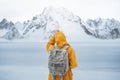 Young woman in yellow jacket travel while her holidays and looking away winter mountain